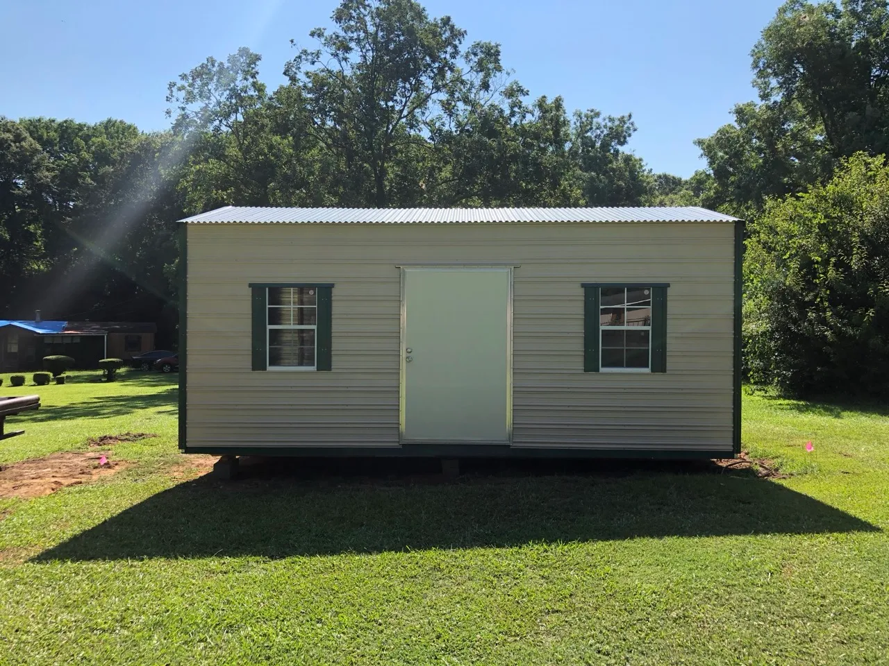 Tan aluminum shed with green trim